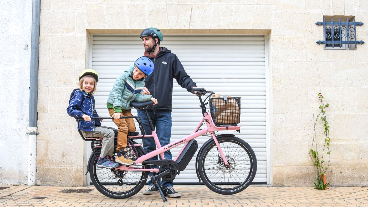Père transportant deux enfants sur un vélo cargo électrique, illustration assurance VAE cargo